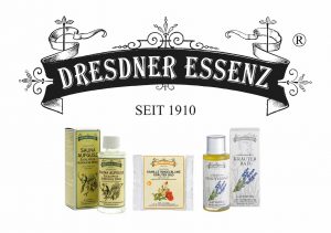 Die traditionellen Produkte von Dresdner Essenz Sauna-Aufguss "Eucalyptus - Nordische Birke", Kamille Ringelblume Kräuter Bad und aromatisches Kräuterbad stehen nebeneinander. Darüber steht in einer Art Banderole in einer älteren, traditionellen Schriftart "Dresdner Essenz" und darunter der Schriftzug "Seit 1910". Die Banderole ist zudem noch mit verschiedenen Verzierungen und verschnörkelten Ornamenten versehen.
