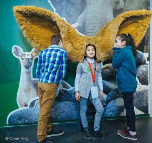 Drei Kinder im Hygienemuseum in Dresden. Die Kinder können entdecken, wie bestimmte Tiere hören können.