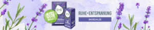Das Badekonzentrat und das Badesalz Ruhe + Entspannung mit Lavendel ist abgebildet. In grauer Schrift steht daneben "Ruhe + Entspannung" und darunter in einem violetten Kästchen in weißer Schrift "Badesalze". Neben dem abgebildeten Badesalz ist ein grüner Kreis abgebildet, in dem der Text "Jetzt mehr Inhalt" in weißer Schrift steht. Der Hintergrund ist leicht violett und transparent und verschiedene Lavendel Zweige sind ebenfalls im Hintergrund zu erkennen, teilweise auch wieder leicht transparent.